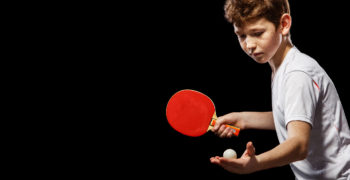 Boy playing table tennis on a black background